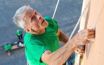 Image of an older man climbing a rock wall.