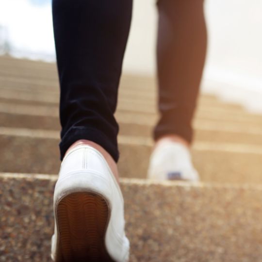 Image of a senior fitness client performing stair-based exercises outdoors.