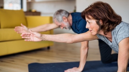 A senior couple undergoing online fitness training at home.