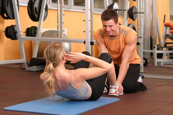 Image of a Standard Fitness Trainer assisting a client in her workout.